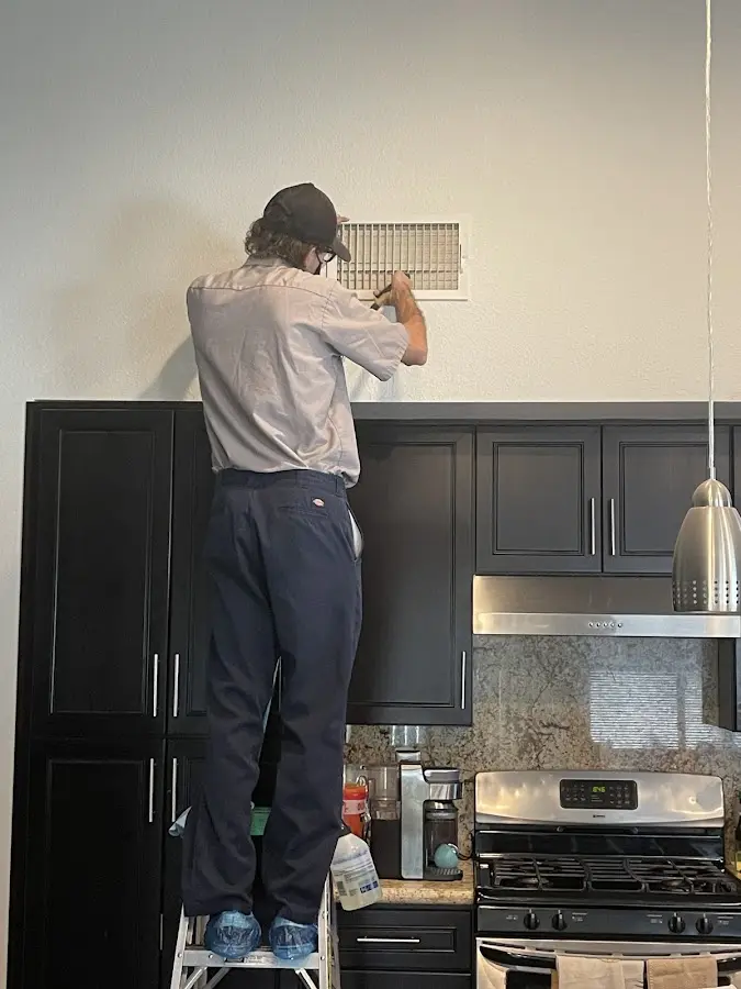 Technician inspecting an air vent during HVAC service in Pompton Lakes